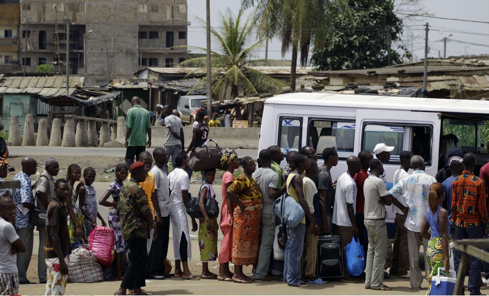 Une foule de personnes fait la queue dans l'espoir d'entrer dans un minibus, dans un quartier d'Abidjan en Côte-d'Ivoire © Rebecca Blackwell/AP/SIPA AP21037074_000003