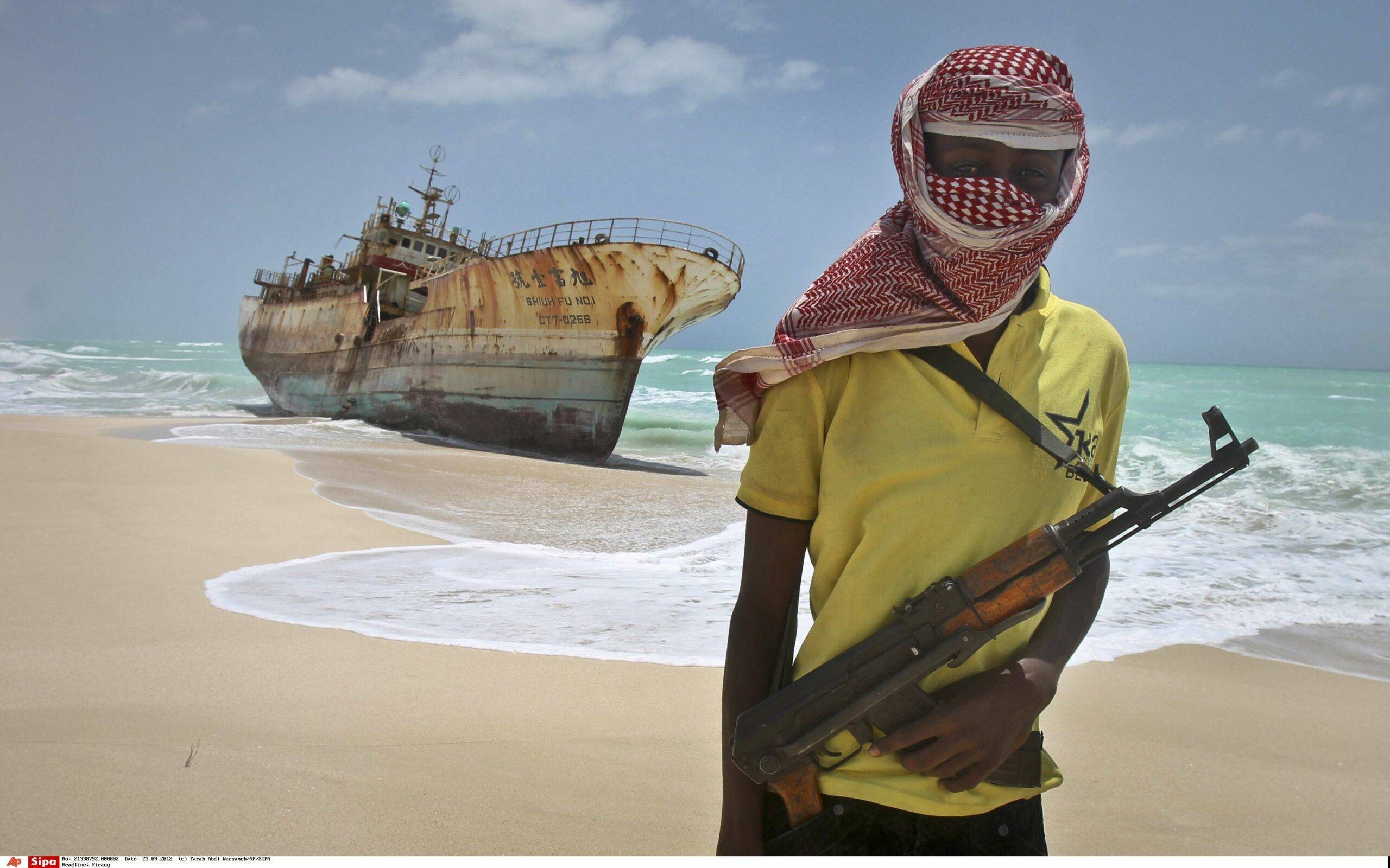 FILE - In this Sunday, Sept. 23, 2012 file photo, masked Somali pirate Hassan stands near a Taiwanese fishing vessel that washed up on shore after the pirates were paid a ransom and released the crew, in the once-bustling pirate den of Hobyo, Somalia. A U.K.-led Piracy Ransom Task Force says the shipping industry must adopt additional measures to ensure that payments aren't made to pirates after a successful attack. (AP Photo/Farah Abdi Warsameh, File)/NAI102/541753079361/SUNDAY, SEPT. 23, 2012 FILE PHOTO/1212121938