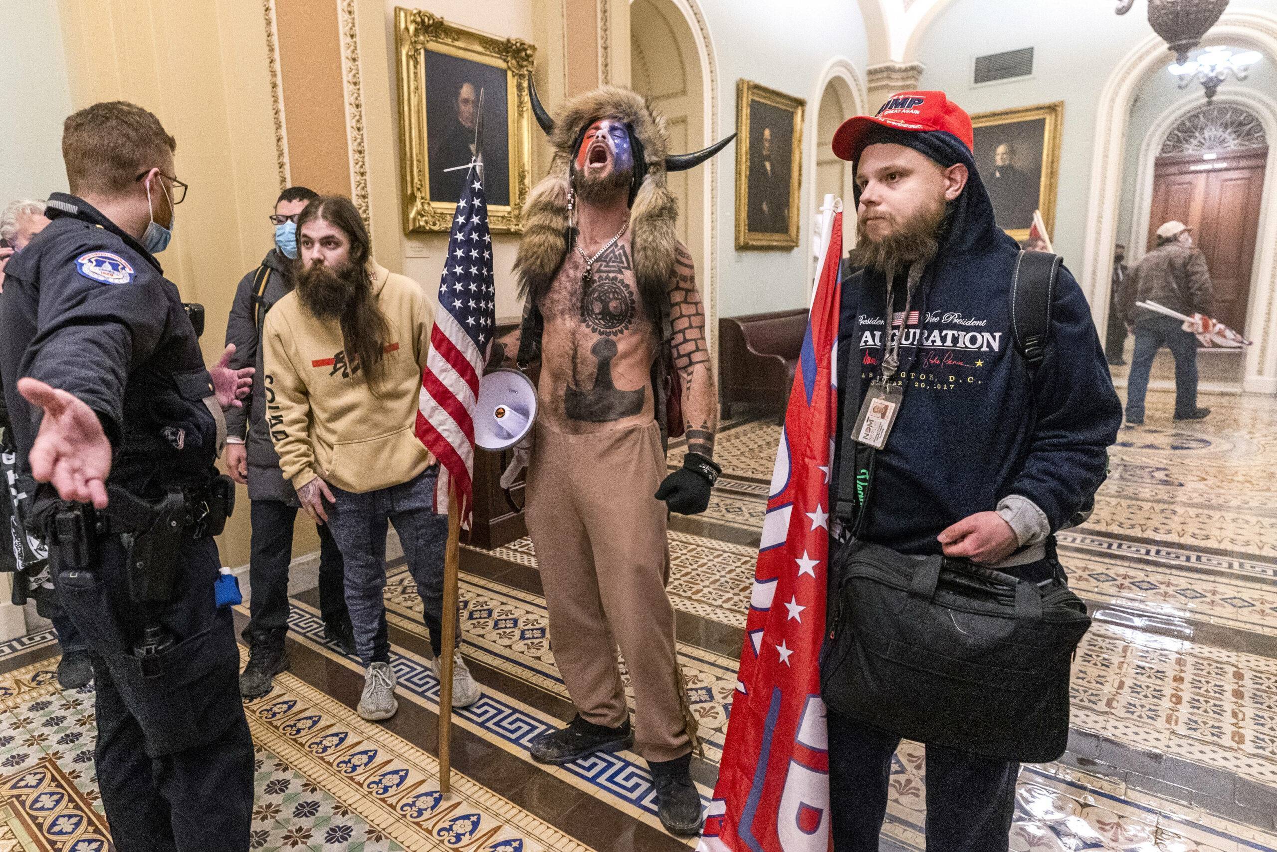 FILE - In this Wednesday, Jan. 6, 2021 file photo, supporters of President Donald Trump, including Jacob Chansley, center with fur hat, are confronted by Capitol Police officers outside the Senate Chamber inside the Capitol in Washington.  Right-wing extremism has previously mostly played out in isolated pockets of America or in smaller cities. In contrast, the deadly attack by rioters on the U.S. Capitol targeted the very heart of government. It brought together members of disparate groups, creating the opportunity for extremists to establish links with each other.  (AP Photo/Manuel Balce Ceneta, File)/NY129/21023678143191//2101231959