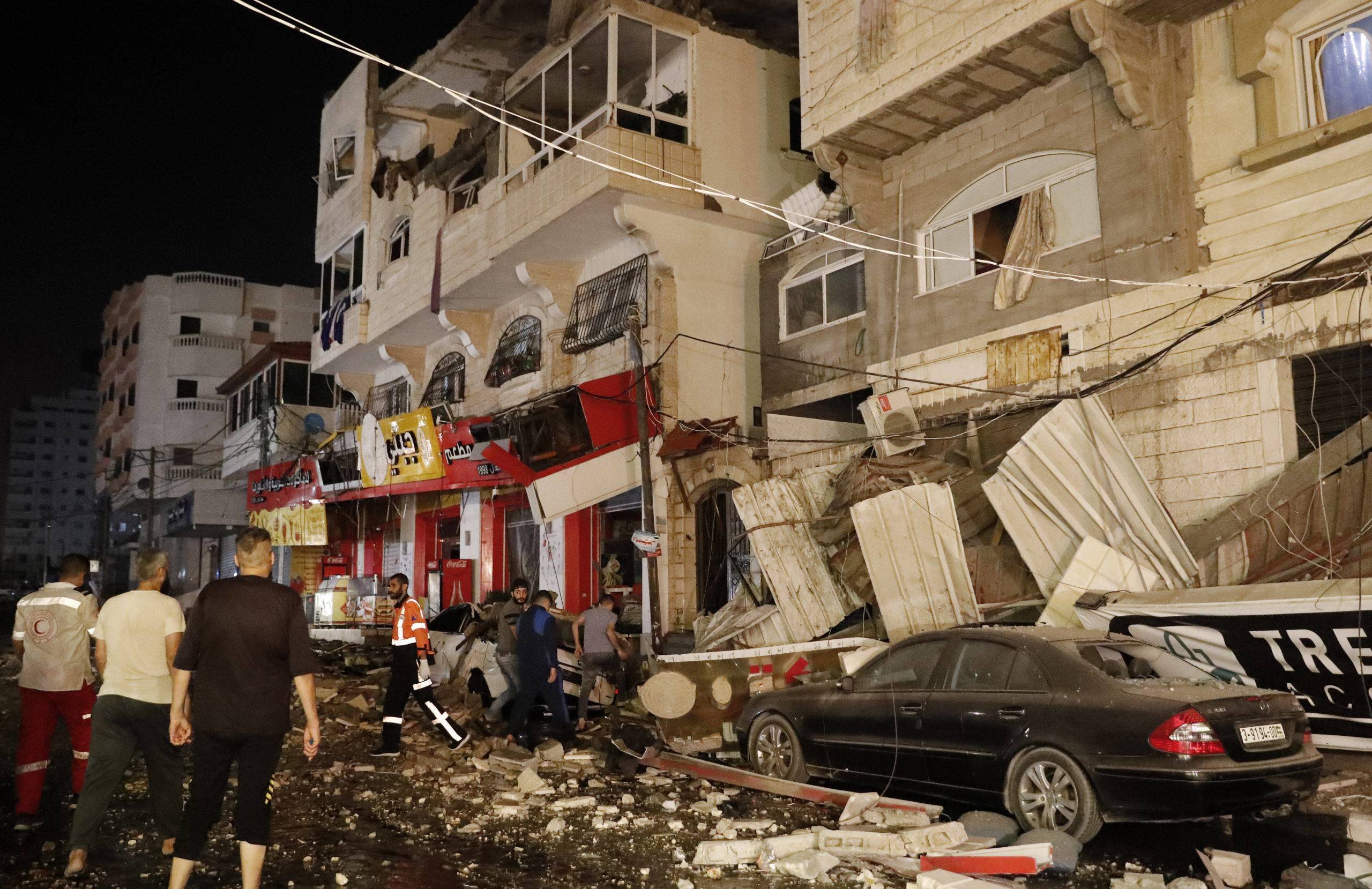 Firefighters and youths inspect destroyed buildings after it was hit by Israeli airstrikes, in Gaza City. May 12, 2021. (AP Photo/Adel Hana)/XAH106/21132065700673//2105120357