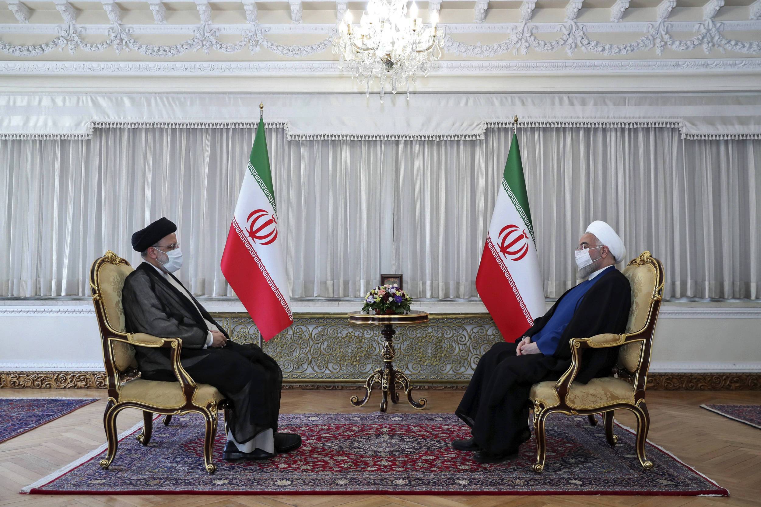 In this photo released by the official website of the office of the Iranian Presidency, President Hassan Rouhani, right, and President-elect Ebrahim Raisi, who is the current judiciary chief, talk during their meeting in Tehran, Iran, Wednesday, June 23, 2021. (Iranian Presidency Office via AP)/ENO102/21174466178733/AP MANDATORY CREDIT./2106231508