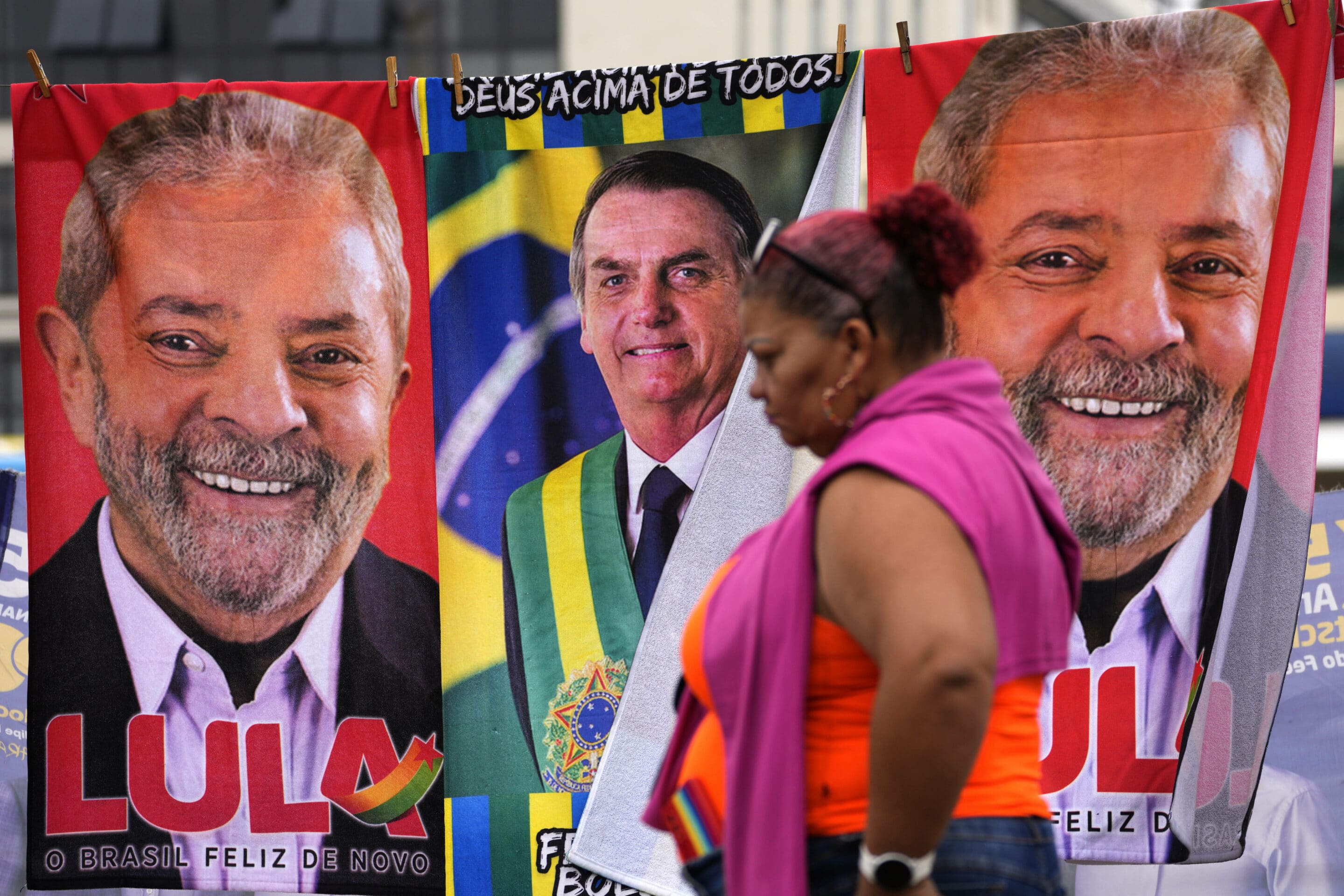 A woman walks past towels emblazoned with images of Brazilian presidential candidates, President Jair Bolsonaro, center, and former President Luiz Inacio Lula da Silva, displayed for sale by a street vendor on a makeshift clothesline, in Brasilia, Brazil, Thursday, Sept. 22, 2022. Brazilians head to polls on Oct. 2 to elect a president, vice president, governors and senators.  (AP Photo/Eraldo Peres)/XEP103/22265640112791//2209222007